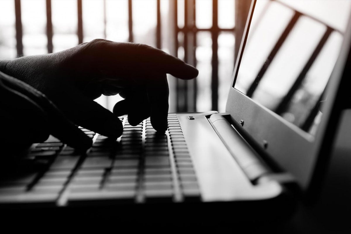 silhouette of hands typing on a laptop