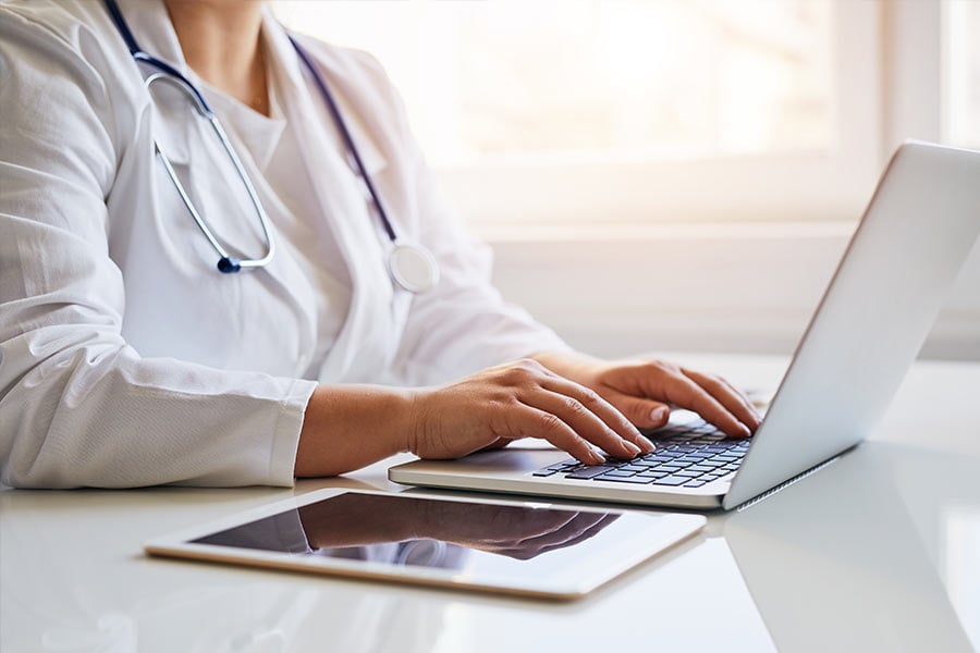 Doctor using a laptop with tablet on table