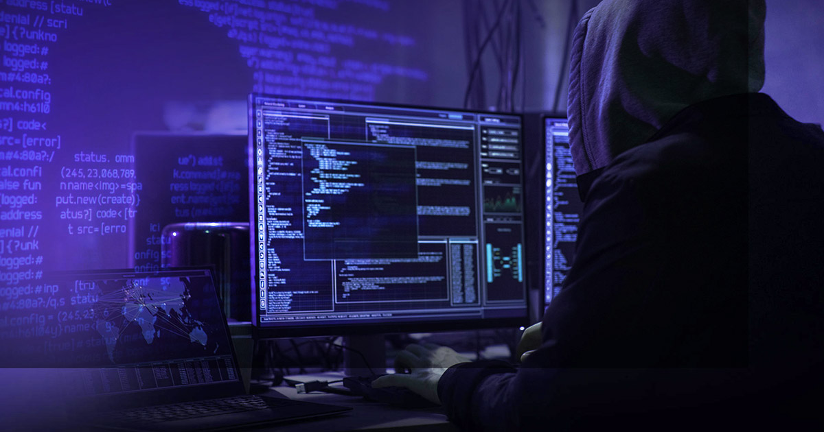 man hacking into computer with code on the wall in the background