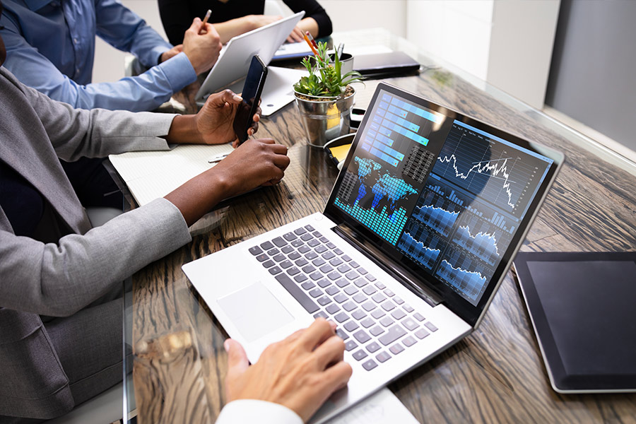 Business people working on laptop with graphs and charts on screen