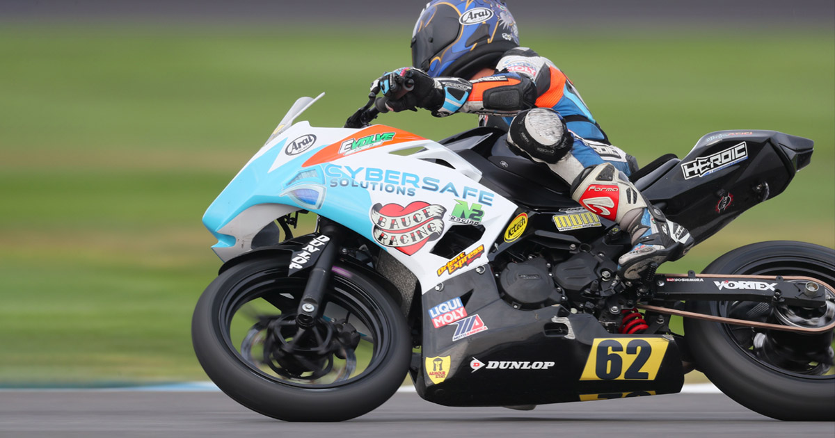 Action shot of motorcycle racer zooming down the road with a Cybersafe Logo on the body of the motorcycle